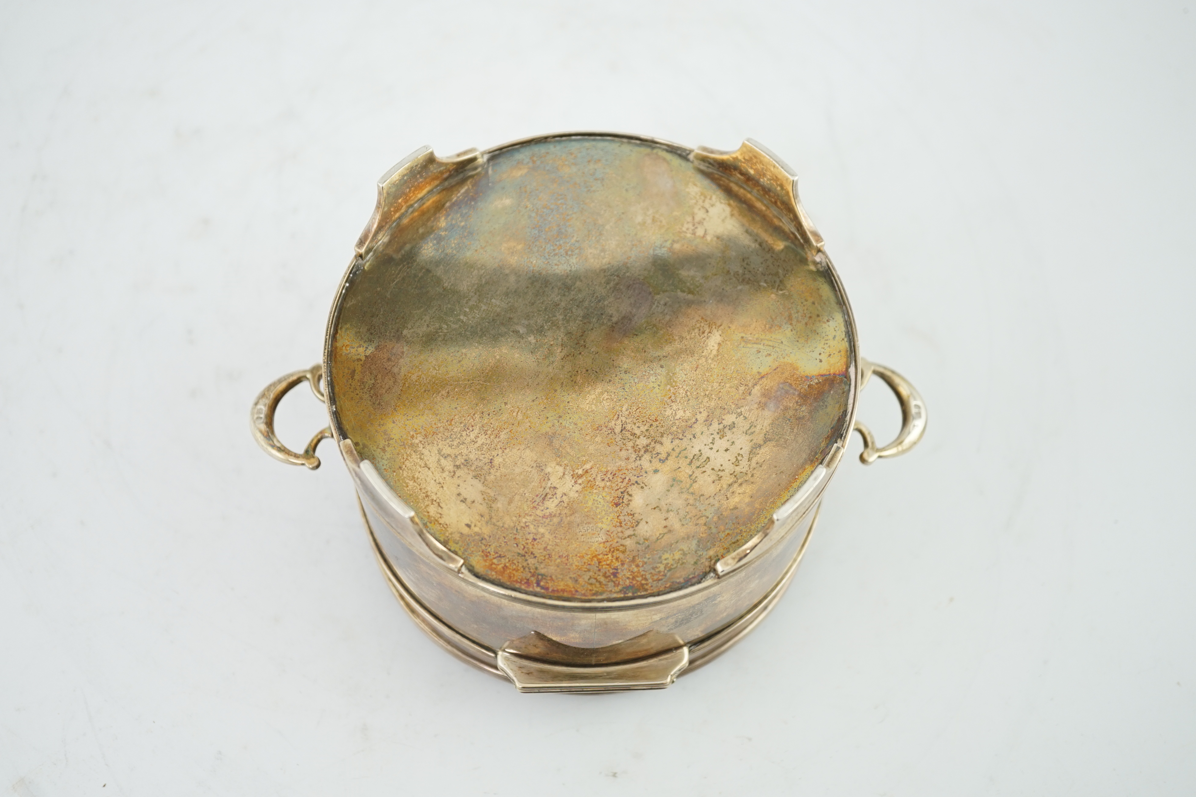 A George V silver circular two handed biscuit box, with hinged cover, by Asprey & Co Ltd